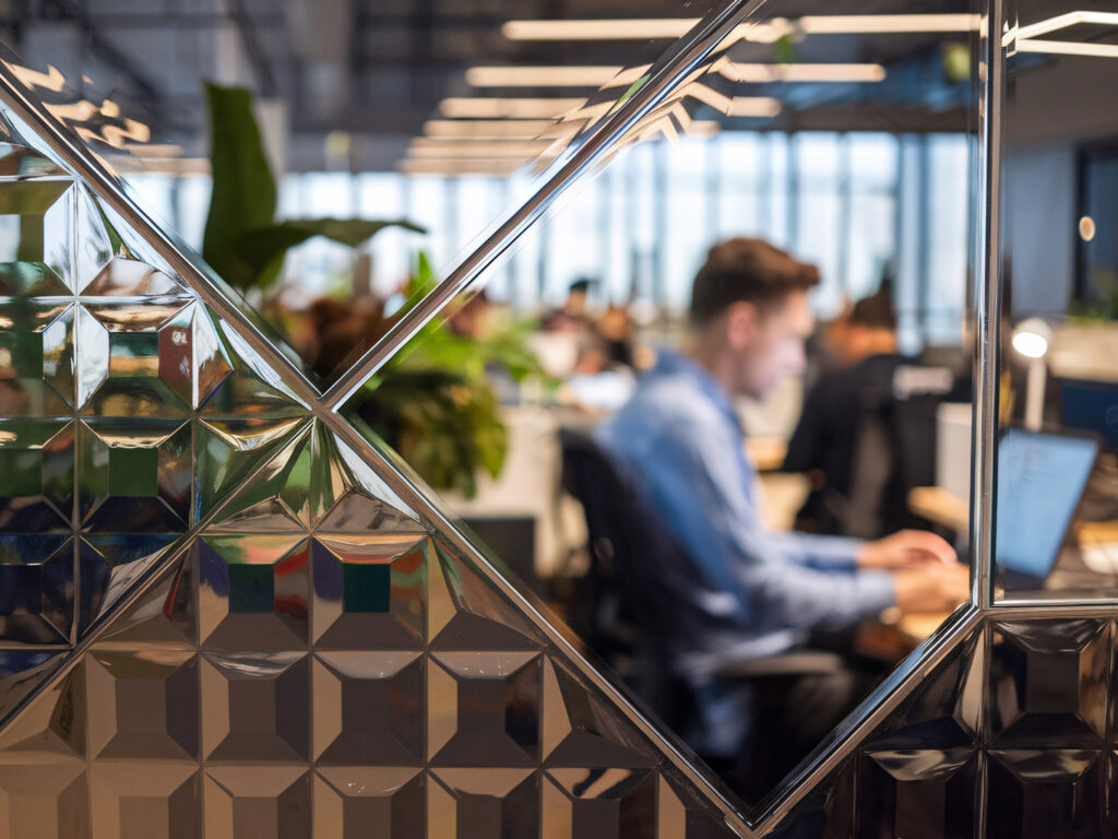 Man typing on laptop through a window