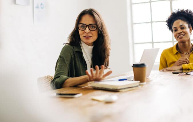 Woman with glasses speaking in a meeting in a conference room