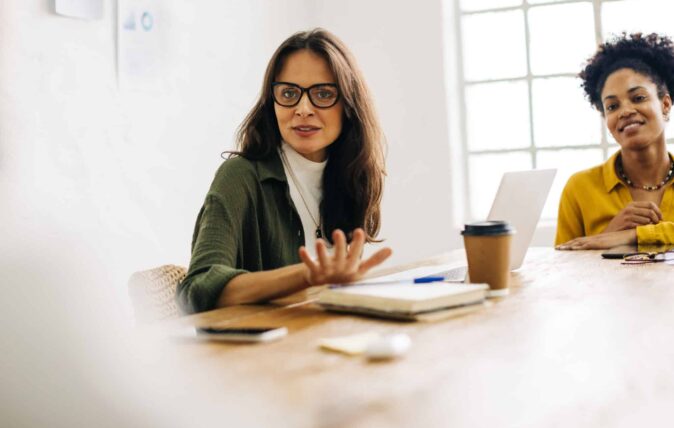 Woman with glasses speaking in a meeting in a conference room