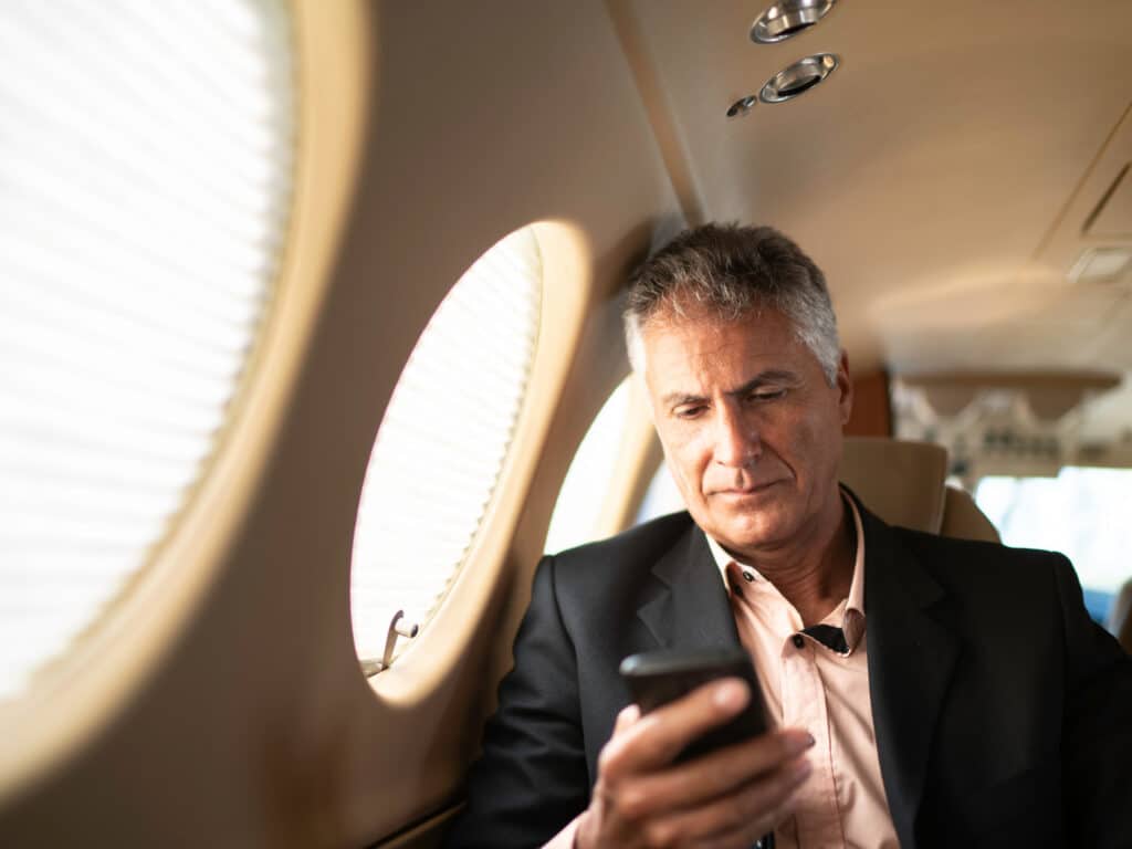 A male executive on an airplane looking at his phone