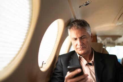 A male executive on an airplane looking at his phone