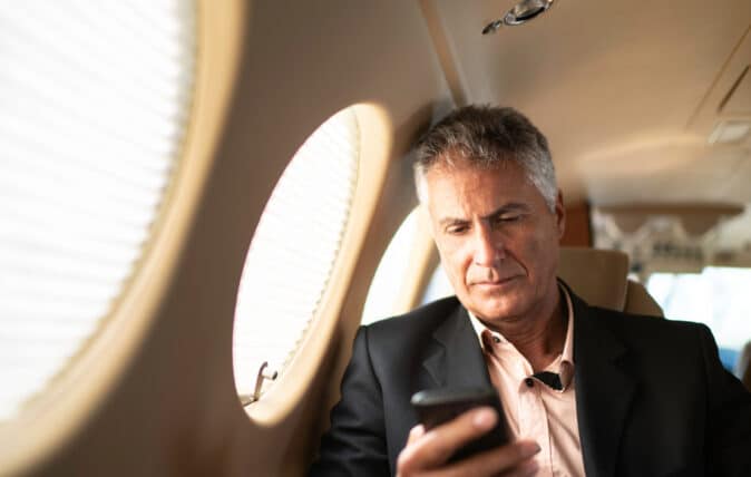 A male executive on an airplane looking at his phone