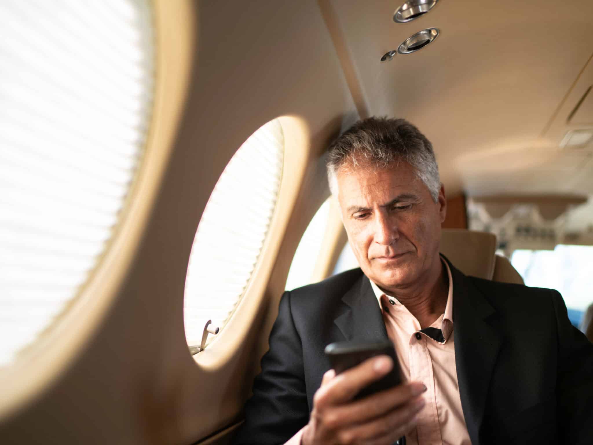 A male executive on an airplane looking at his phone
